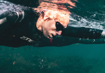 man swimming in wetsuit